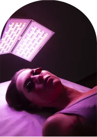 Femme de trois quart avec des lunettes de protection pendant un soin de la peau LED, couleur rose
